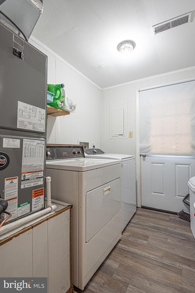 washroom with crown molding, wood-type flooring, washer and dryer, and heating utilities