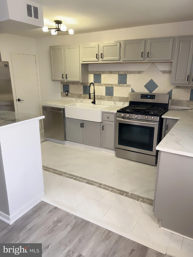 kitchen featuring gray cabinets, sink, and appliances with stainless steel finishes