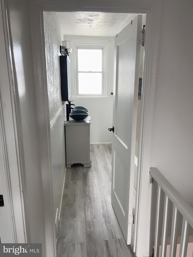 hall featuring a textured ceiling and light wood-type flooring