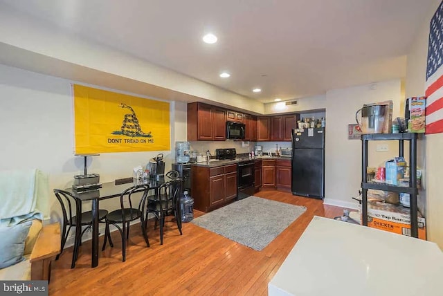 kitchen with light hardwood / wood-style floors and black appliances