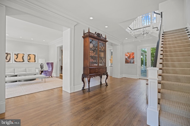 foyer entrance featuring wood-type flooring, crown molding, and a notable chandelier