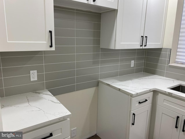 kitchen with white cabinets, light stone counters, and tasteful backsplash