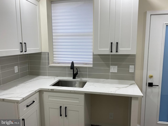 kitchen with white cabinetry, light stone counters, tasteful backsplash, and sink