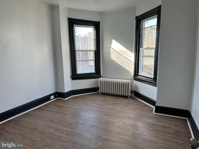 unfurnished room with dark hardwood / wood-style floors, radiator heating unit, and a healthy amount of sunlight