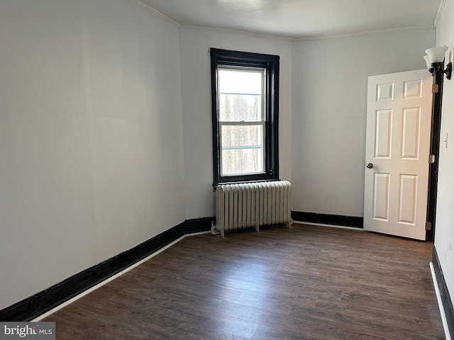 unfurnished room featuring dark hardwood / wood-style floors, ornamental molding, and radiator heating unit