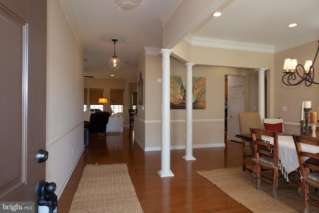 dining area featuring dark hardwood / wood-style floors, decorative columns, ornamental molding, and a chandelier