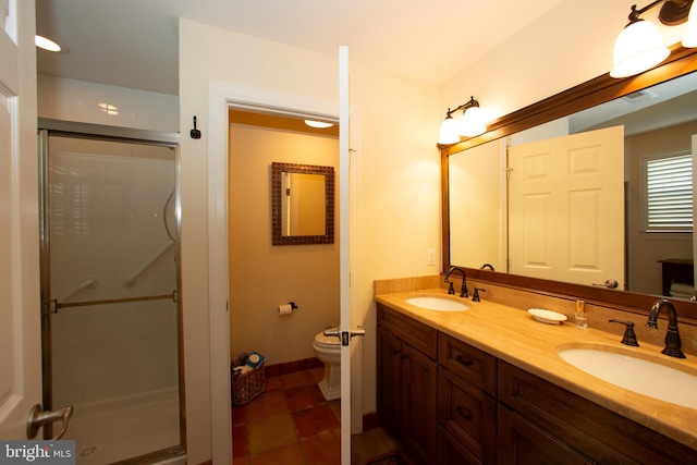 bathroom featuring tile flooring, double sink, a shower with door, toilet, and vanity with extensive cabinet space