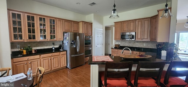 kitchen featuring stainless steel appliances, tasteful backsplash, and decorative light fixtures