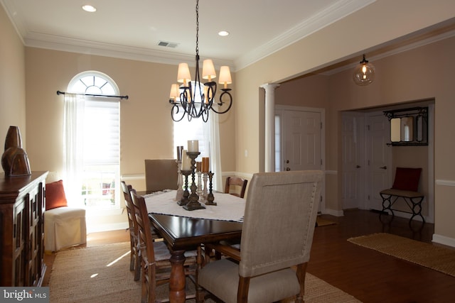 dining room with an inviting chandelier, decorative columns, crown molding, and dark hardwood / wood-style flooring