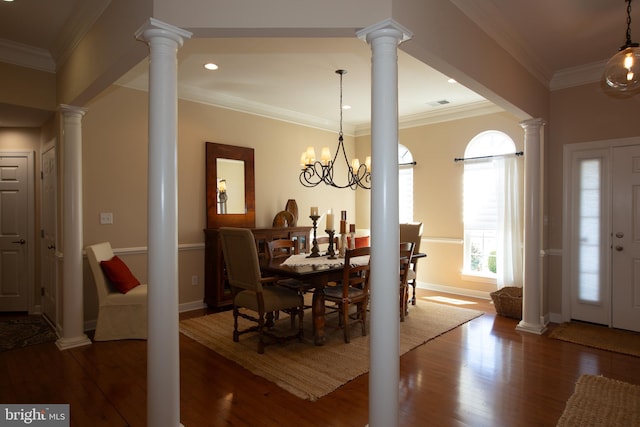 dining area featuring an inviting chandelier, crown molding, dark wood-type flooring, and decorative columns