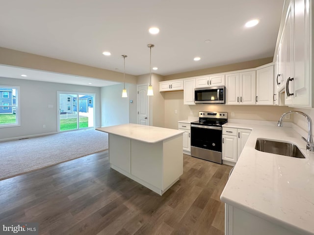 kitchen featuring a kitchen island, sink, white cabinets, appliances with stainless steel finishes, and light stone counters