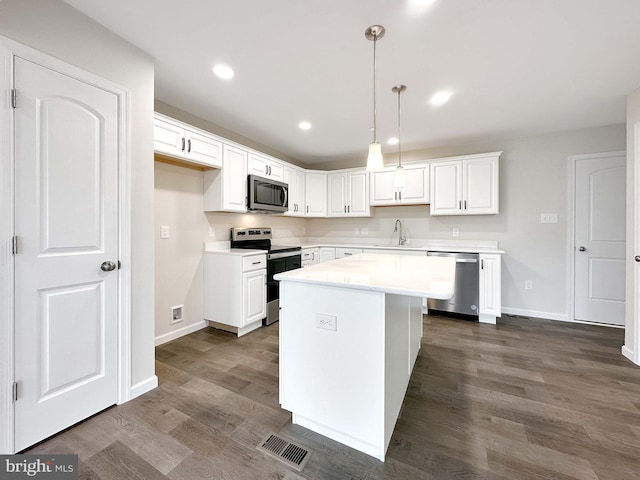 kitchen featuring sink, a center island, decorative light fixtures, white cabinetry, and appliances with stainless steel finishes