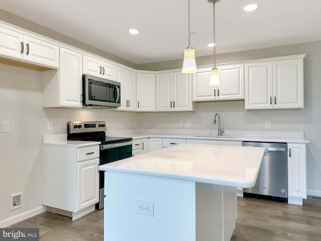 kitchen with white cabinets, stainless steel appliances, sink, and a kitchen island