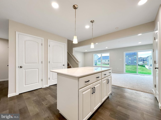 kitchen featuring a kitchen island, white cabinets, dark wood-type flooring, and decorative light fixtures