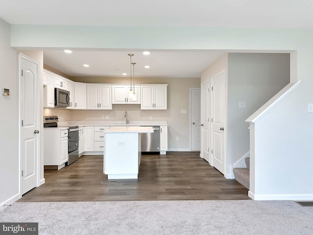 kitchen featuring white cabinets, hanging light fixtures, appliances with stainless steel finishes, dark wood-type flooring, and a center island