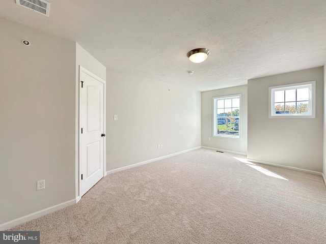 carpeted empty room with a textured ceiling