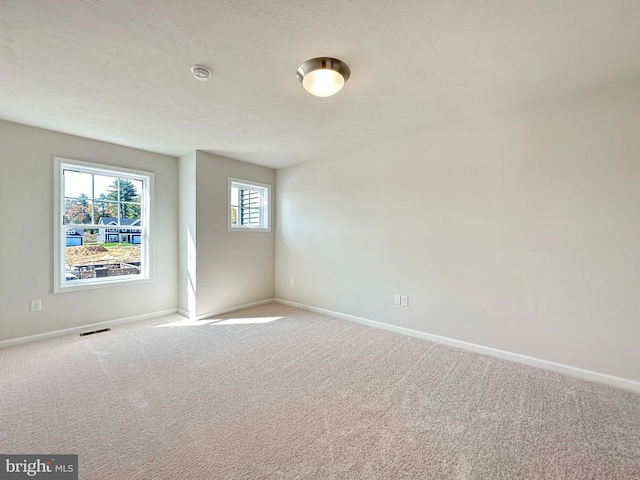 carpeted spare room with a textured ceiling