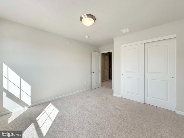 unfurnished bedroom featuring a closet and light colored carpet