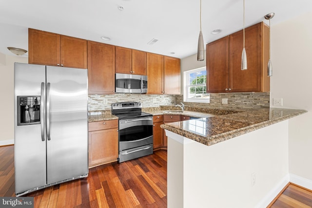 kitchen featuring dark hardwood / wood-style flooring, hanging light fixtures, stainless steel appliances, and tasteful backsplash