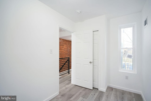 interior space with light hardwood / wood-style flooring and brick wall