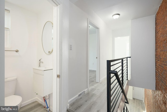 bathroom featuring hardwood / wood-style floors, brick wall, and toilet