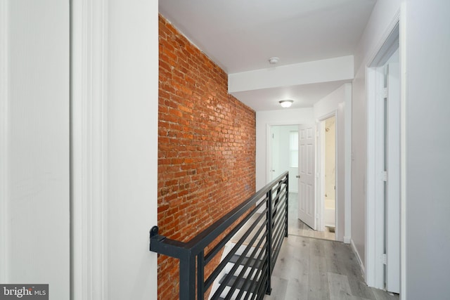 hall with brick wall and light wood-type flooring