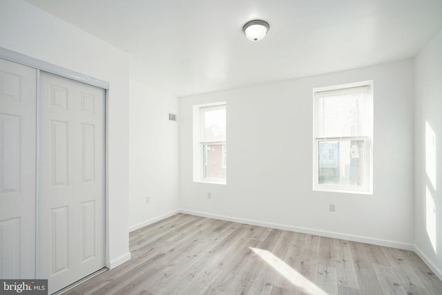 unfurnished bedroom with light hardwood / wood-style flooring and a closet