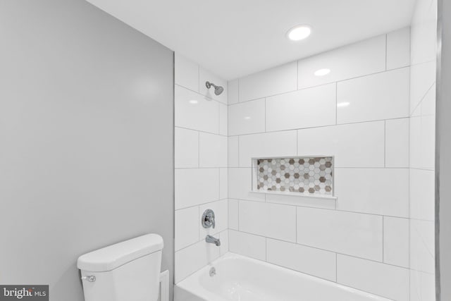 bathroom with tiled shower / bath combo and toilet