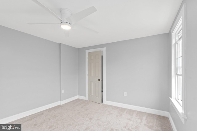 empty room featuring ceiling fan and light colored carpet