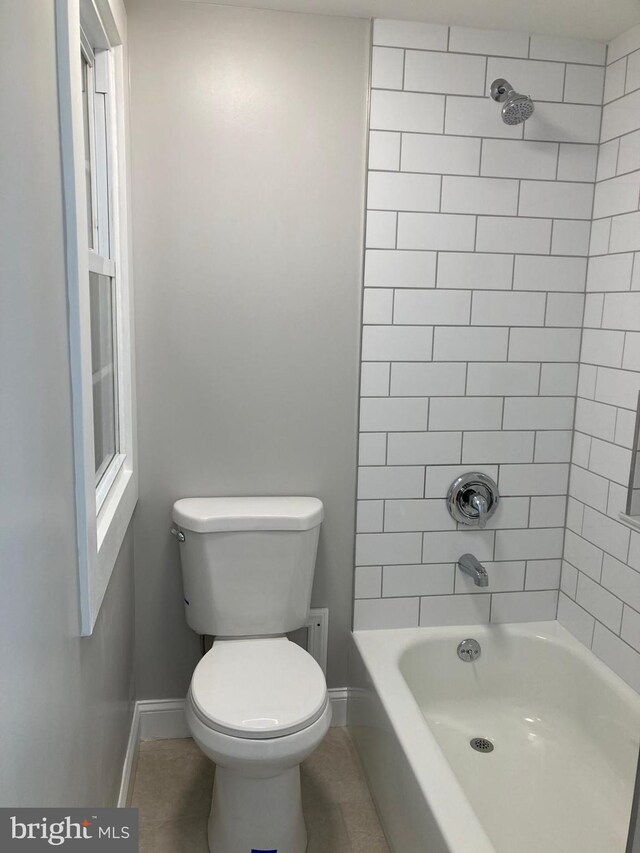 bathroom with tile patterned floors, tiled shower / bath combo, and toilet