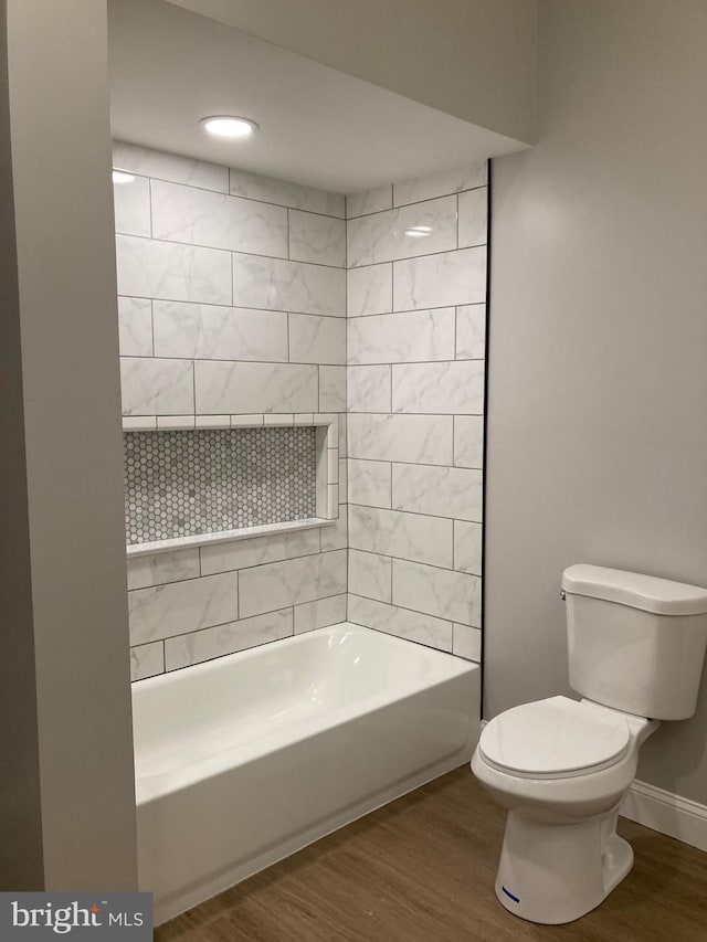 bathroom with toilet, wood-type flooring, and tiled shower / bath