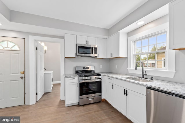 kitchen with light stone countertops, white cabinetry, sink, and appliances with stainless steel finishes