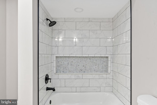 bathroom with tiled shower / bath combo and toilet