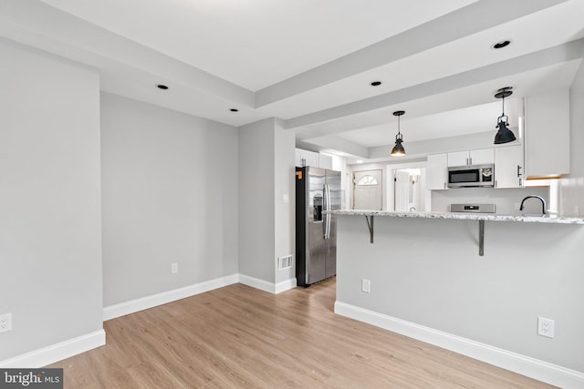 kitchen with white cabinetry, stainless steel appliances, a kitchen breakfast bar, a raised ceiling, and kitchen peninsula