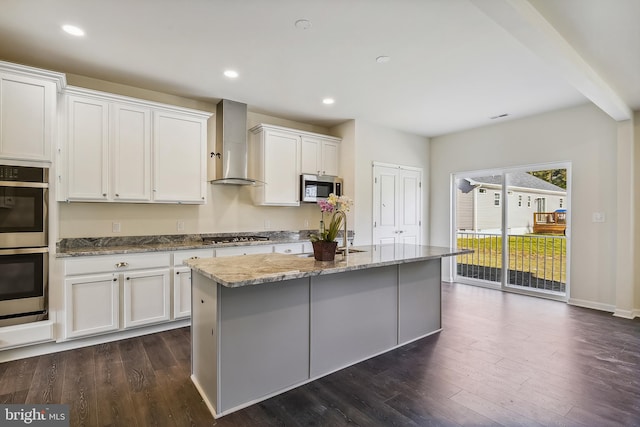 kitchen with light stone counters, dark hardwood / wood-style flooring, white cabinets, stainless steel appliances, and wall chimney range hood