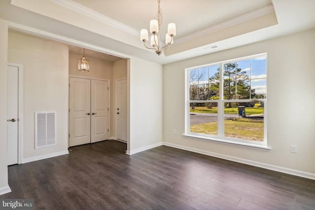 spare room with a raised ceiling, a notable chandelier, and dark wood-type flooring