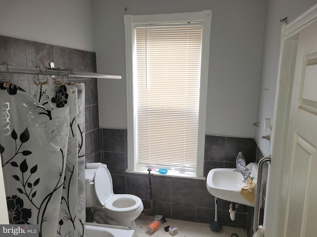 bathroom with tile walls, sink, curtained shower, and toilet