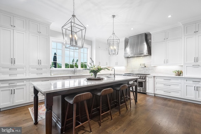 kitchen with a kitchen breakfast bar, white cabinets, stainless steel range, dark wood-type flooring, and wall chimney exhaust hood