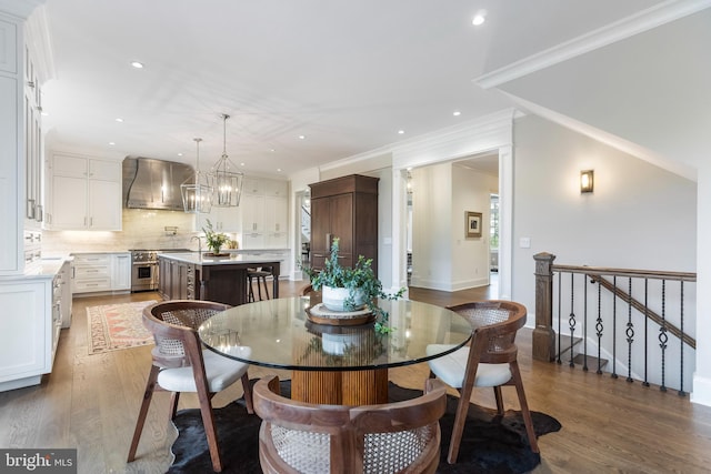 dining area featuring crown molding, hardwood / wood-style floors, sink, and an inviting chandelier