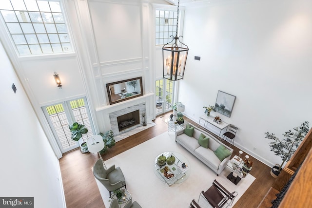 living room featuring a premium fireplace, hardwood / wood-style floors, and a high ceiling