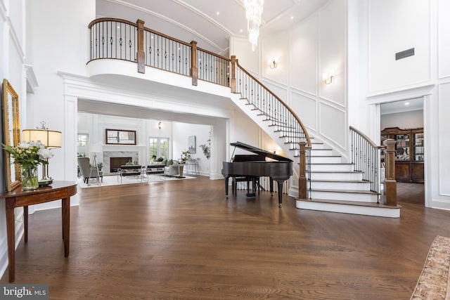 entryway with a towering ceiling, ornamental molding, a high end fireplace, and dark hardwood / wood-style flooring