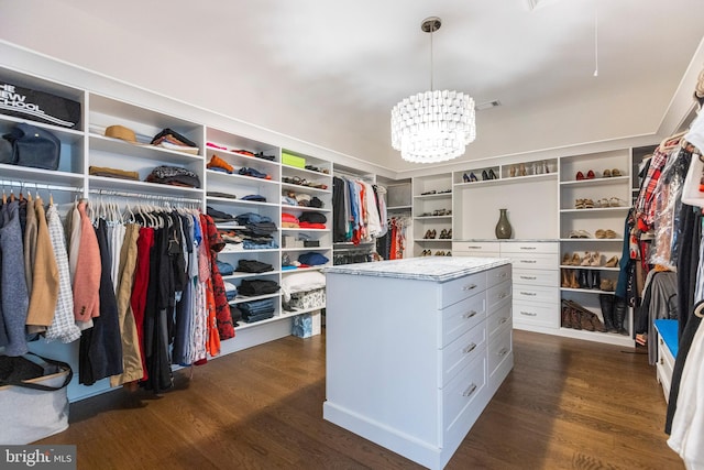 walk in closet with an inviting chandelier and dark hardwood / wood-style flooring