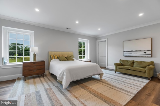 bedroom featuring multiple windows, dark hardwood / wood-style floors, and ornamental molding