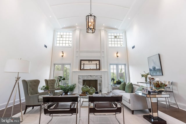 living room featuring a high end fireplace, high vaulted ceiling, a notable chandelier, and hardwood / wood-style flooring