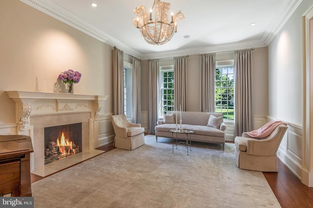 sitting room featuring a high end fireplace, wood-type flooring, an inviting chandelier, and crown molding