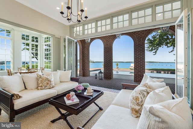 sunroom with a water view and an inviting chandelier