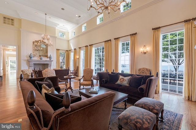 living room featuring light hardwood / wood-style flooring, a towering ceiling, a chandelier, and ornamental molding