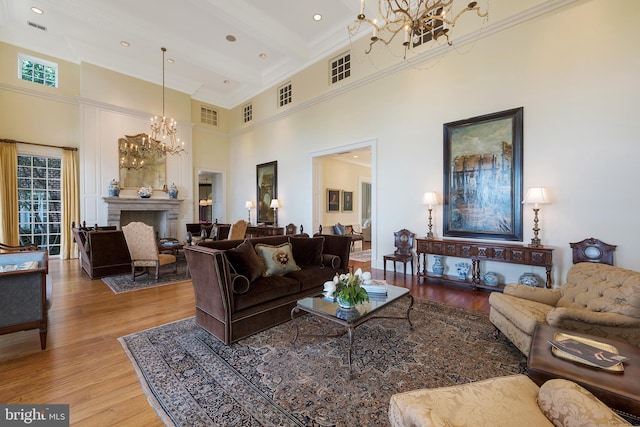 living room featuring beamed ceiling, wood-type flooring, a high ceiling, and a notable chandelier