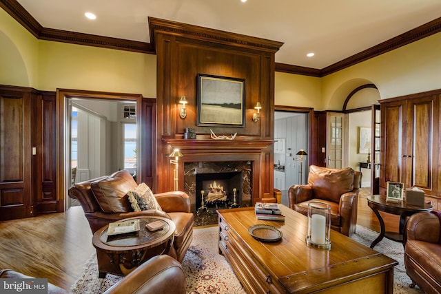 living room with a premium fireplace, light hardwood / wood-style floors, and ornamental molding