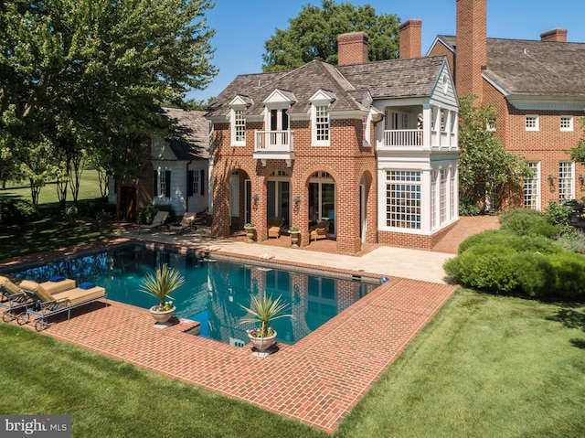 rear view of property with a yard, outdoor lounge area, a patio area, and a balcony